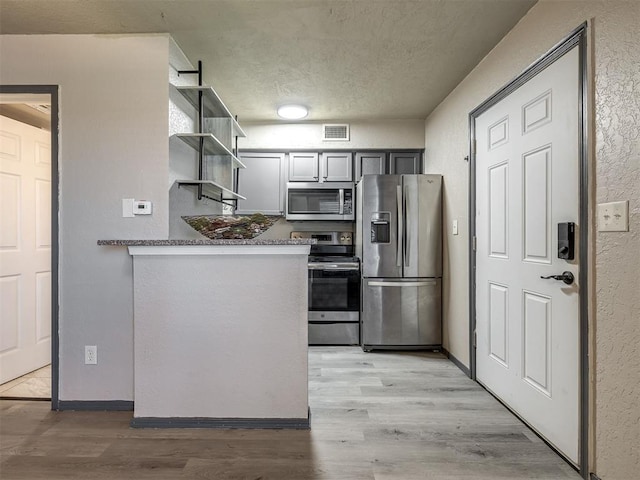 11530 N May Ave Unit D303, Oklahoma City, OK 73120 - kitchen featuring stainless steel appliances, open shelves, light wood-style floors, a textured wall, and a textured ceiling