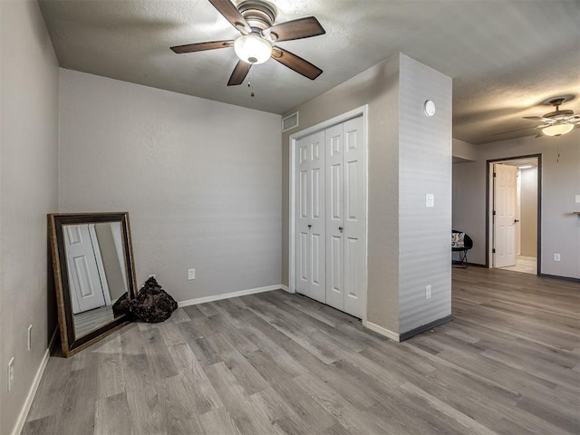11530 N May Ave Unit D303, Oklahoma City, OK 73120 - unfurnished bedroom featuring light wood finished floors, a closet, a ceiling fan, and a textured ceiling