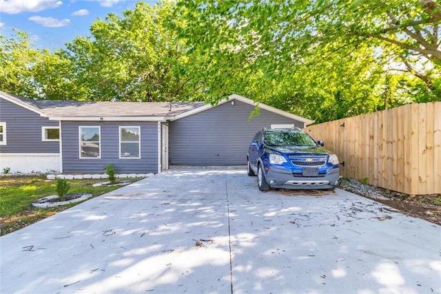 view of side of home featuring fence and driveway