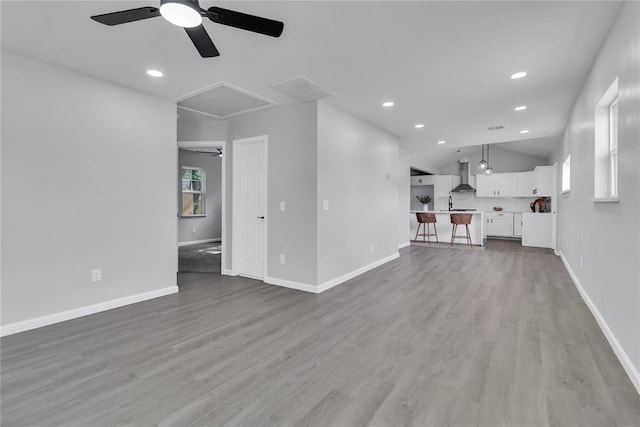 unfurnished living room featuring ceiling fan, wood finished floors, vaulted ceiling, baseboards, and recessed lighting