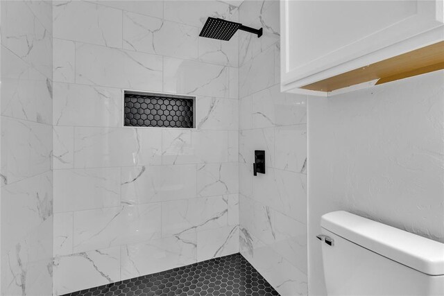bathroom featuring tiled shower and toilet