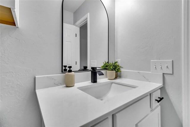 bathroom with a textured wall and vanity