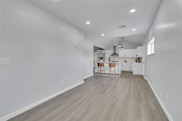unfurnished living room featuring lofted ceiling, light wood finished floors, baseboards, and recessed lighting