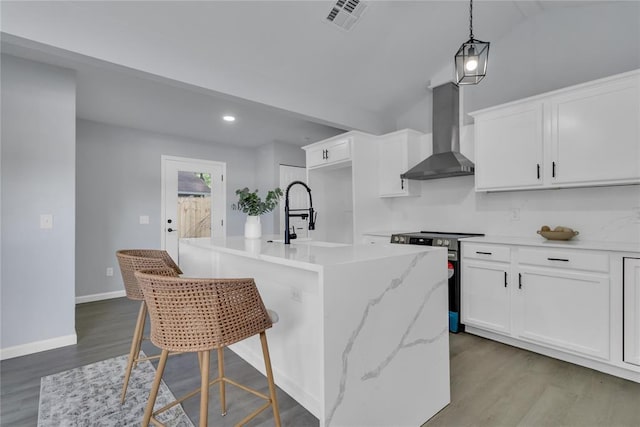 kitchen featuring wall chimney exhaust hood, electric range, a sink, wood finished floors, and an island with sink