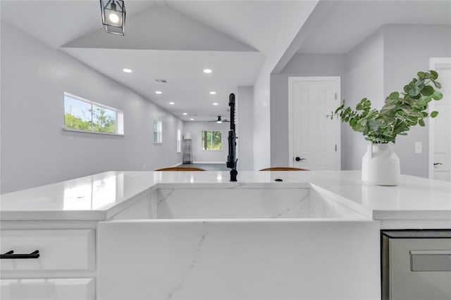 kitchen with recessed lighting, ceiling fan, white cabinets, lofted ceiling, and light stone countertops
