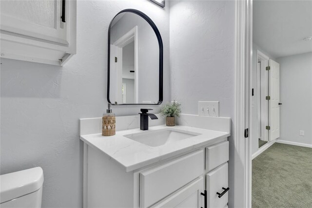 half bath featuring vanity and toilet