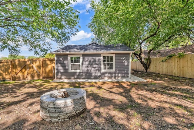 back of house featuring a fenced backyard and a fire pit