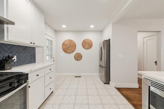 2237 NW 30th St, Oklahoma City, OK 73112 - kitchen with appliances with stainless steel finishes, baseboards, white cabinets, wall chimney range hood, and backsplash