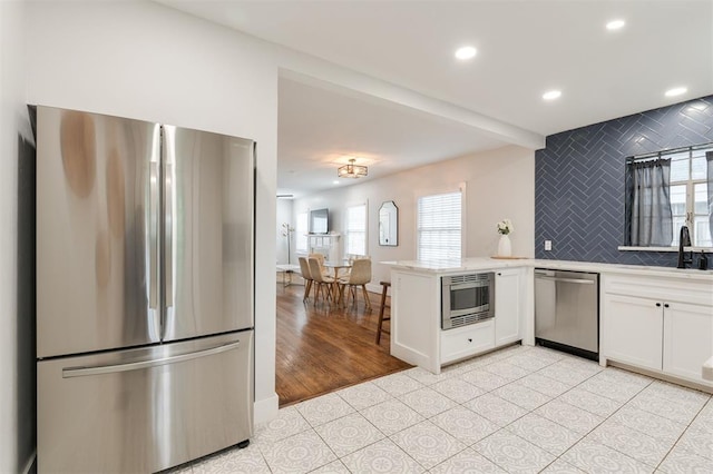 2237 NW 30th St, Oklahoma City, OK 73112 - kitchen featuring appliances with stainless steel finishes, a peninsula, white cabinets, healthy amount of natural light, and recessed lighting
