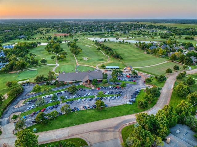 aerial view at dusk of a water view and view of golf course