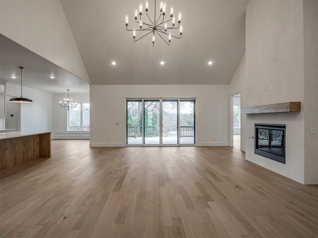 6201 Canopy Ln, Edmond, OK 73025 - unfurnished living room with a chandelier, high vaulted ceiling, a glass covered fireplace, recessed lighting, and baseboards