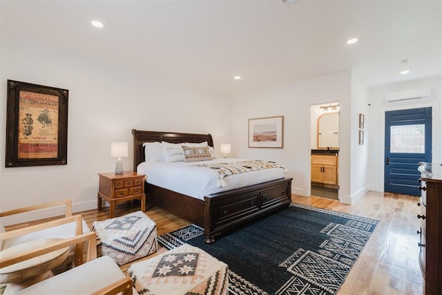 221 Alameda St, Norman, OK 73069 - bedroom featuring a wall unit AC, light wood-style flooring, baseboards, recessed lighting, and connected bathroom