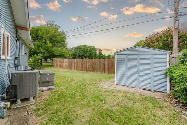 221 Alameda St, Norman, OK 73069 - yard at dusk featuring a shed, central air condition unit, and an outbuilding