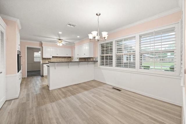 3222 Wilshire Ter, Oklahoma City, OK 73116 - kitchen with a chandelier, ornamental molding, a ceiling fan, a breakfast bar area, and a peninsula