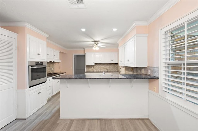 3222 Wilshire Ter, Oklahoma City, OK 73116 - kitchen featuring oven, ceiling fan, a peninsula, white cabinets, and crown molding