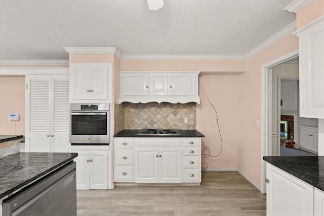 3222 Wilshire Ter, Oklahoma City, OK 73116 - kitchen featuring appliances with stainless steel finishes, light wood-type flooring, decorative backsplash, ornamental molding, and white cabinetry