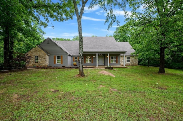 view of front of property featuring stone siding, a porch, a front yard, and roof with shingles