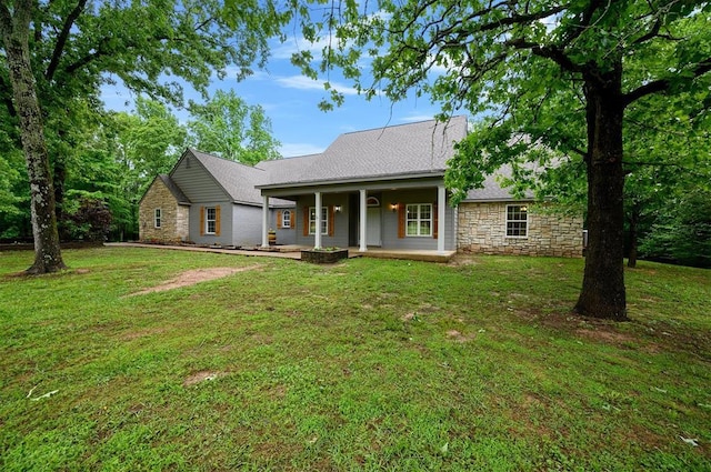 view of front of property featuring stone siding, a front lawn, a shingled roof, and a porch