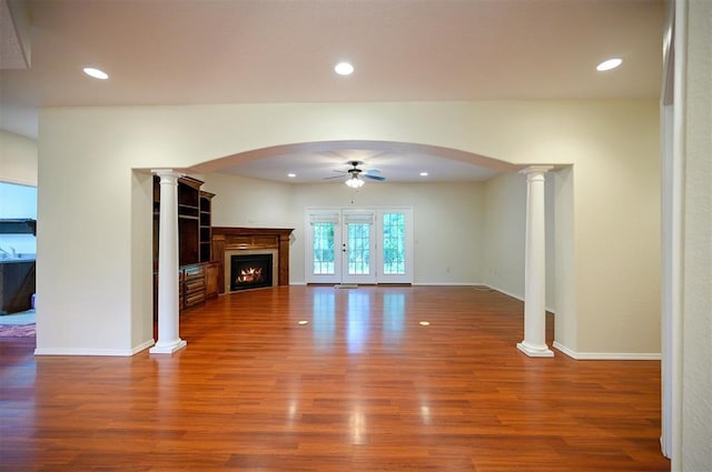 unfurnished living room featuring a ceiling fan, arched walkways, wood finished floors, and recessed lighting