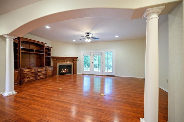 unfurnished living room featuring decorative columns, ceiling fan, wood finished floors, a lit fireplace, and recessed lighting