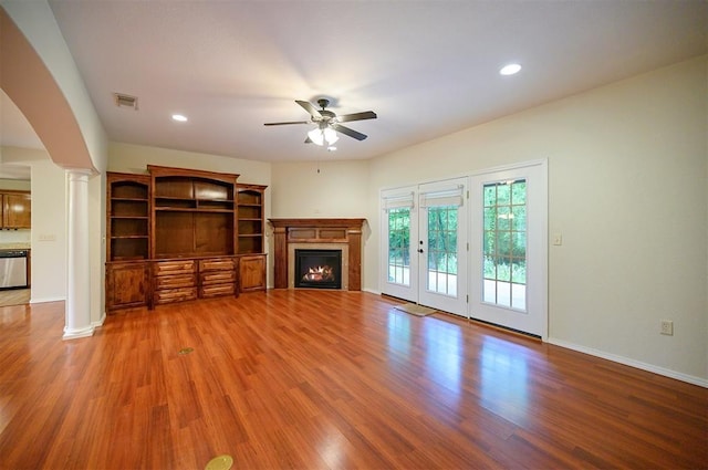 unfurnished living room with ornate columns, ceiling fan, a lit fireplace, wood finished floors, and recessed lighting