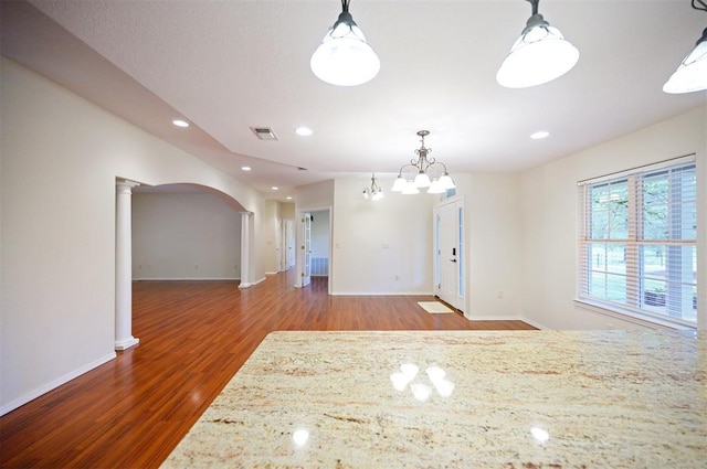 unfurnished dining area with wood finished floors, ornate columns, baseboards, arched walkways, and recessed lighting
