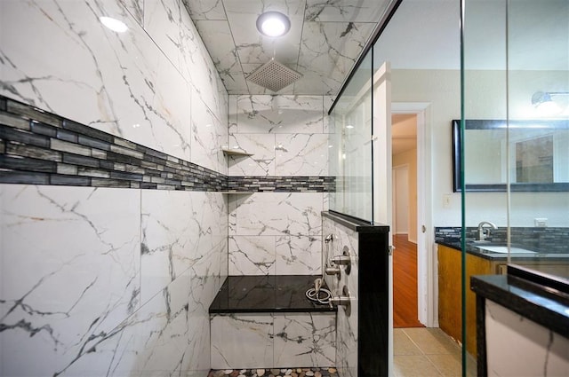 full bath featuring vanity, a marble finish shower, and tile patterned flooring