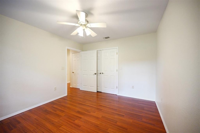 unfurnished bedroom with wood finished floors, baseboards, ceiling fan, and a closet