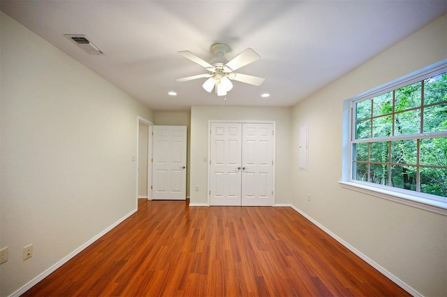 unfurnished bedroom featuring wood finished floors, baseboards, a closet, recessed lighting, and a ceiling fan