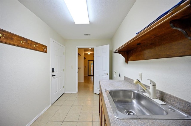 kitchen featuring a sink, light tile patterned floors, open shelves, and baseboards