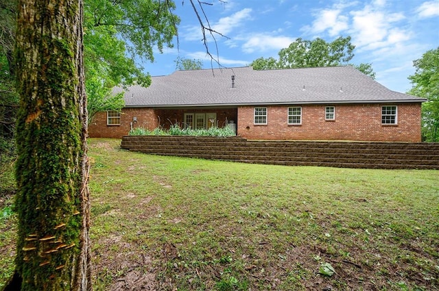 back of property featuring a lawn and brick siding