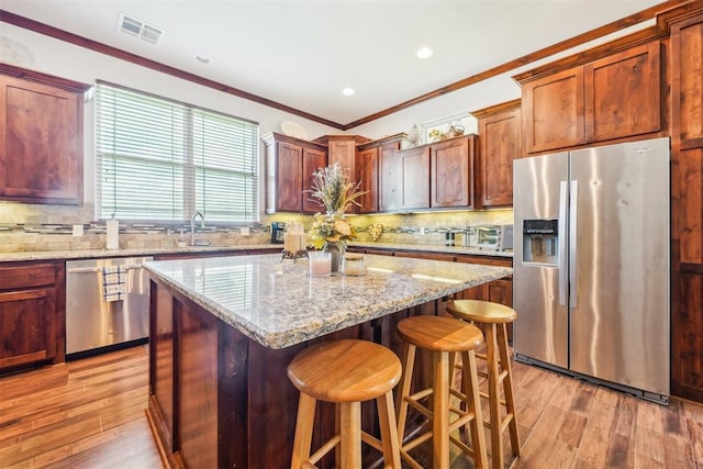 18421 State Highway 24, Purcell, OK 73080 - kitchen featuring stainless steel appliances, light wood-style flooring, ornamental molding, a center island, and a kitchen bar