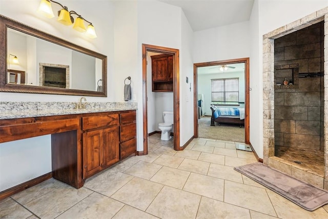 18421 State Highway 24, Purcell, OK 73080 - ensuite bathroom featuring vanity, toilet, a tile shower, baseboards, and a ceiling fan
