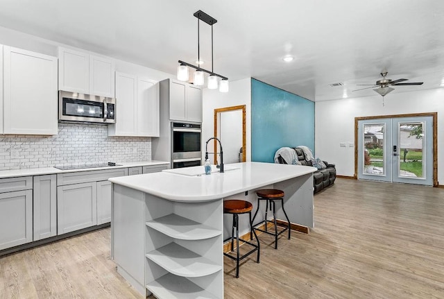kitchen with stainless steel microwave, open shelves, open floor plan, black electric cooktop, and decorative backsplash