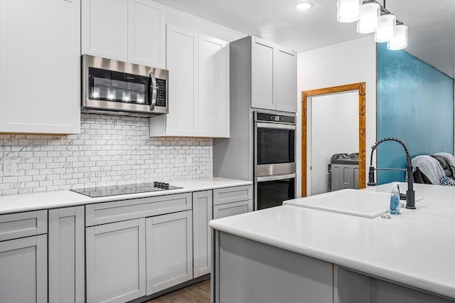 kitchen featuring stainless steel appliances, a sink, light countertops, and backsplash