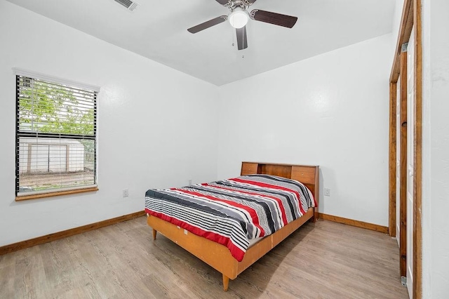 bedroom featuring baseboards, wood finished floors, and a ceiling fan