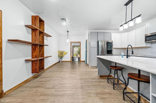 502 W Pine St, Tuttle, OK 73089 - kitchen featuring stainless steel appliances, light wood-type flooring, decorative backsplash, a kitchen breakfast bar, and decorative light fixtures