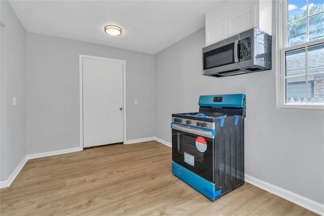 503 W Martin St, El Reno, OK 73036 - kitchen with appliances with stainless steel finishes, light wood-style floors, white cabinets, and baseboards