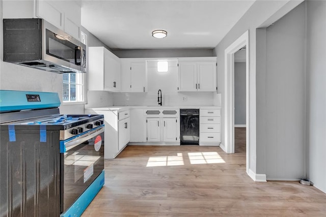 503 W Martin St, El Reno, OK 73036 - kitchen with stainless steel appliances, a sink, light countertops, white cabinets, and light wood-style floors