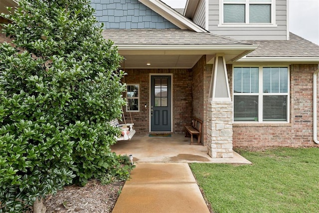 18337 Tombstone Trl, Norman, OK 73072 - view of exterior entry featuring brick siding, a shingled roof, a porch, and a yard