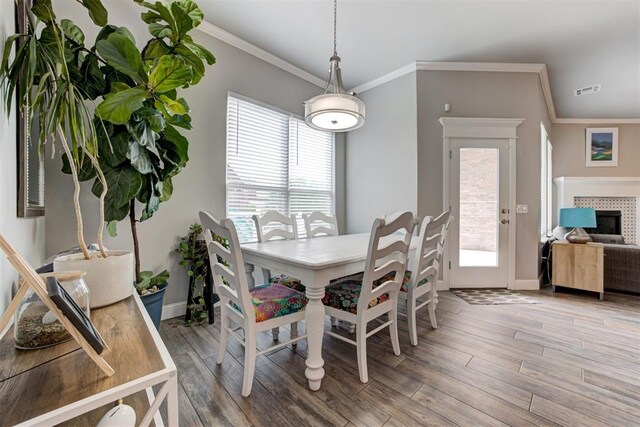 18337 Tombstone Trl, Norman, OK 73072 - dining space featuring baseboards, light wood-type flooring, ornamental molding, and a tiled fireplace