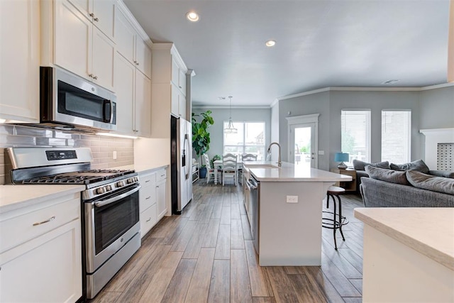 18337 Tombstone Trl, Norman, OK 73072 - kitchen featuring appliances with stainless steel finishes, a sink, light countertops, a kitchen breakfast bar, and crown molding