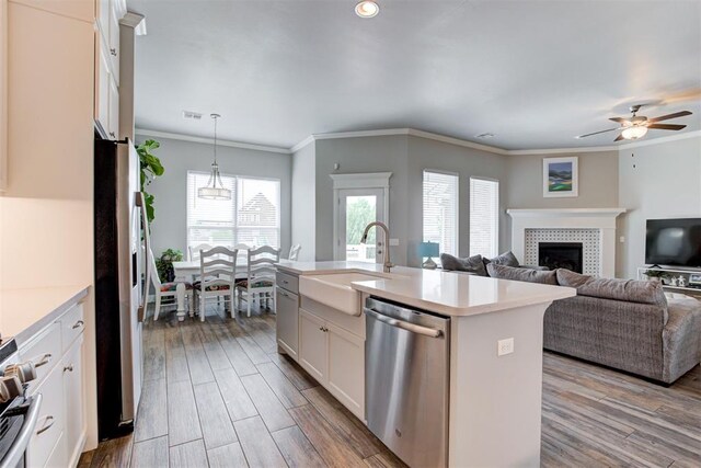 18337 Tombstone Trl, Norman, OK 73072 - kitchen with stainless steel appliances, a sink, a tile fireplace, light countertops, and wood finished floors