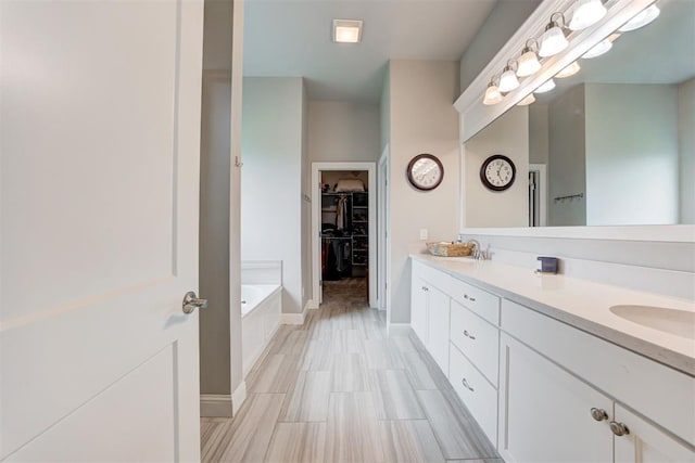 18337 Tombstone Trl, Norman, OK 73072 - full bathroom with a walk in closet, double vanity, a garden tub, and baseboards