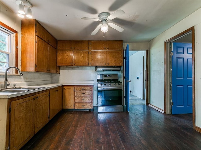 3617 N Westmont St, Oklahoma City, OK 73118 - kitchen featuring stainless steel gas range oven, a sink, brown cabinetry, dark wood-style flooring, and light countertops