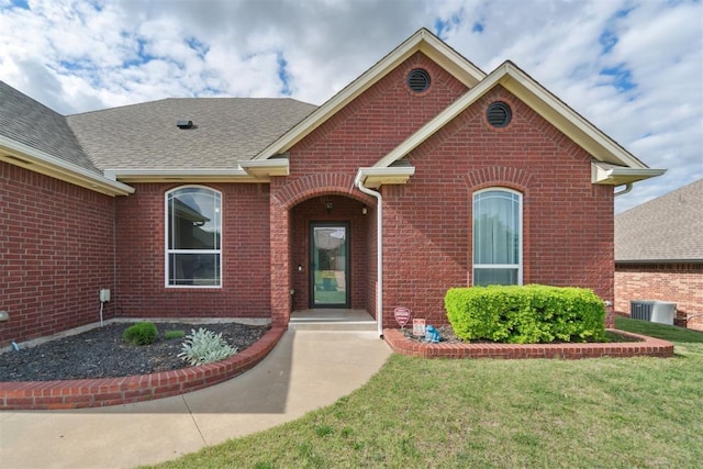 11423 Village Ave, Midwest City, OK 73130 - view of front of home featuring brick siding, central air condition unit, a shingled roof, and a front yard