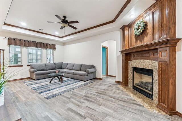 11423 Village Ave, Midwest City, OK 73130 - living area featuring a tray ceiling, a ceiling fan, light wood-type flooring, arched walkways, and a fireplace