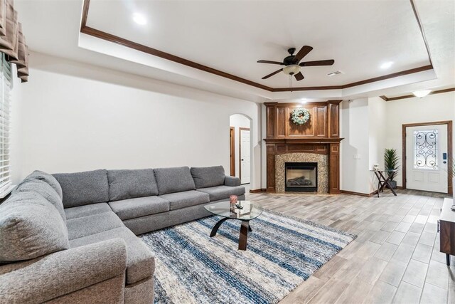 11423 Village Ave, Midwest City, OK 73130 - living area with a tray ceiling, a large fireplace, a ceiling fan, arched walkways, and crown molding