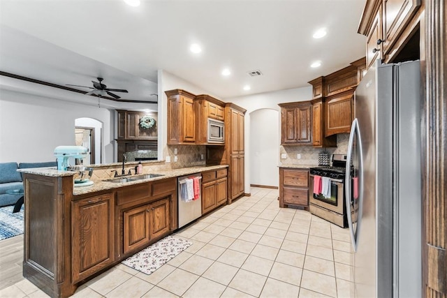 11423 Village Ave, Midwest City, OK 73130 - kitchen with arched walkways, a sink, appliances with stainless steel finishes, a ceiling fan, and backsplash