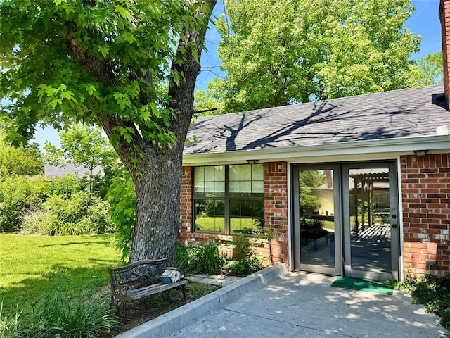 202 Flanders Dr, Chickasha, OK 73018 - entrance to property featuring brick siding, a shingled roof, and a yard